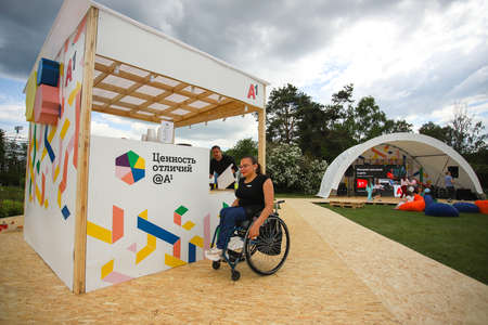 Minsk. Belarus - 06.04.2021: A disabled woman in a wheelchair in a park against the backdrop of greenery surrounded by people.のeditorial素材