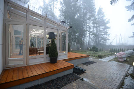Belarus - 26.02.2015 - Glass terrace overlooking the misty forest. Own house in a forest.のeditorial素材