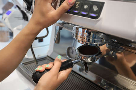 Minsk. Belarus - 06.06.2021: A cute barista makes coffee in a coffee machine.のeditorial素材