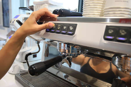 Minsk. Belarus - 06.06.2021: A cute barista makes coffee in a coffee machine.のeditorial素材