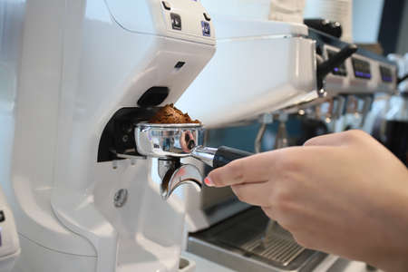 Minsk. Belarus - 06.06.2021:A woman makes aromatic, fresh coffee in a coffee machine.