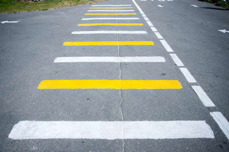 Pedestrian crossing, white-yellow stripes on a road.の写真素材