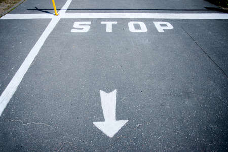A barrier and the STOP sign on the road. White-red barrier on the road. Green along the edges of the road. High quality photoの写真素材