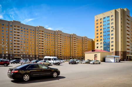 Nur-Sultan. Kazakhstan: 04.09.2013 - Parking in the residential center. Residential buildings are yellow, a residential complex against a blue sky. Nur-Sultan.のeditorial素材