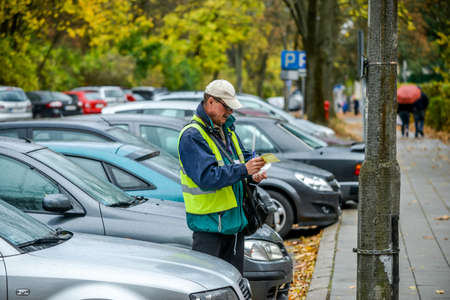 Bialystok. Poland: 20.10.2014 - A parking attendant in a yellow bright yellow jacket works in a paid parking lot in the city of Bialystok.のeditorial素材
