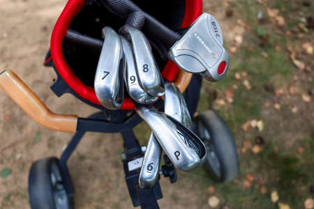 Minsk. Belarus - 25.07.2021 - Golf clubs in a red bag close-up green grass backgroundのeditorial素材