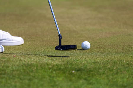 A golfer makes a putter on the ball on the greenの写真素材