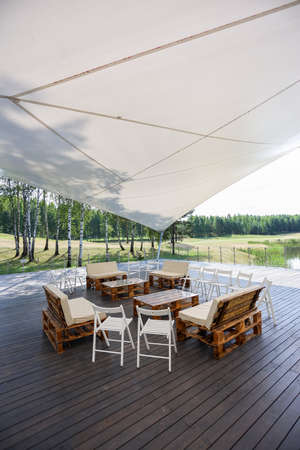 Wooden furniture in a tent in the middle of the green field. High quality photoの写真素材