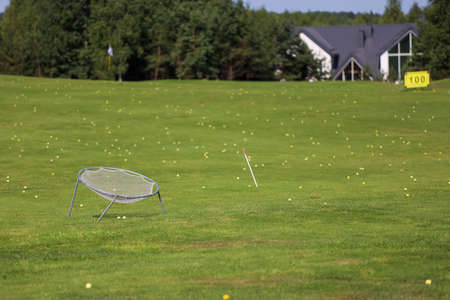 Driving range ongolf course on a green golf course with a forest in the background.の写真素材