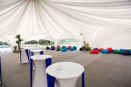 Tables are blue and white in a tent decorated with fabric.の写真素材