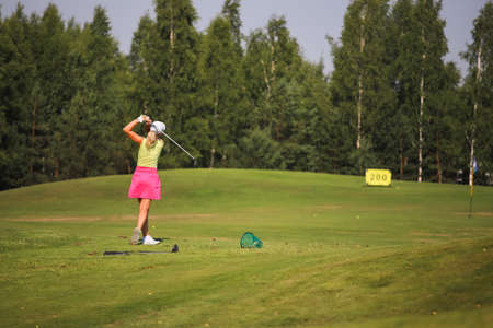 Minsk. Belarus 02.07.2021 - Golfer with a putter on the field. Nearby there is a forest, green grass.のeditorial素材