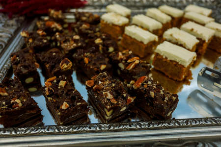 Cookie slices with nuts, cocoa and caramel at buffet table, served on the silver trayの写真素材