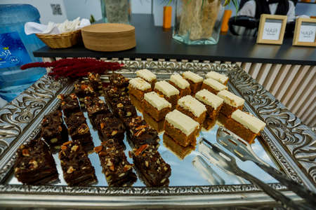 Cookie slices with nuts, cocoa and caramel at buffet table, served on the silver trayの写真素材