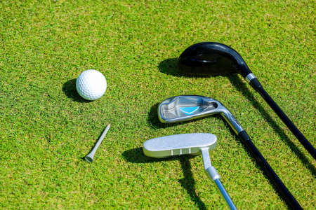 Golf clubs and ball lie on green grass in a rays of the everlasting sun. High quality photoの写真素材