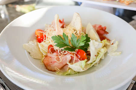 Egg, croutons, tomato, ham salad in a white plate on a table. High quality photoの写真素材