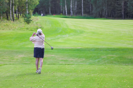 Golfer with a putter on the field. Nearby there is a forest, green grass.の写真素材