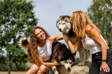 Two womens hugging husky dogs in summer park.の写真素材