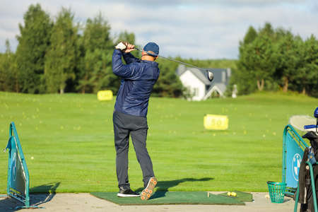 Golfer with a putter on the field. Nearby there is a forest, green grass.の写真素材