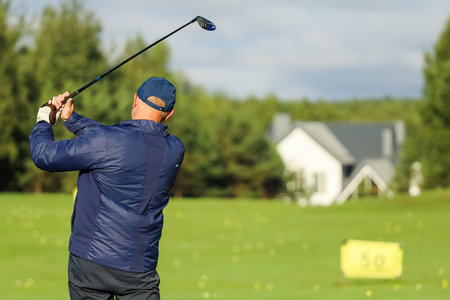 Golfer with a putter on the field. Nearby there is a forest, green grass.の写真素材