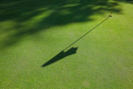 Flag shadow on the golf course with green grass. High quality photoの写真素材