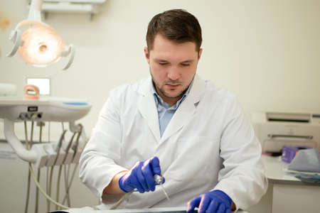 Male dentist smiling and holding tools in his hands. High quality photoの写真素材