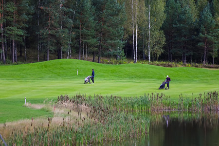 Golf course, landscape, green grass on the background of the forest and a bright sky with clouds. High quality photoの写真素材