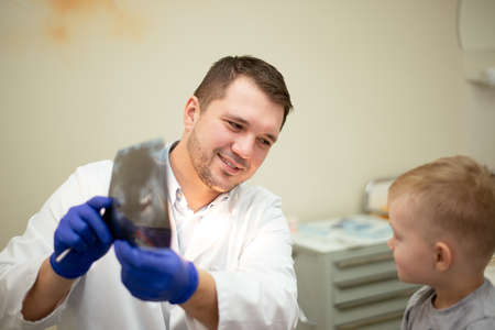 Dentist shows a picture of teeth to the small patient. High quality photoの写真素材