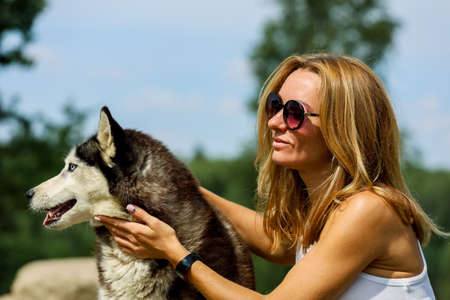 Woman whith her dog hasky in summer parkの写真素材