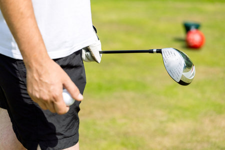 Close up of male golfers hands holding golf club on green grass. Autumnの写真素材