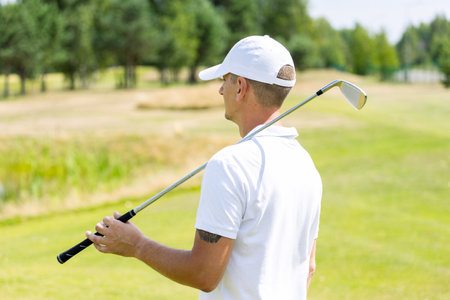 Close up of male golfers hands holding golf club on green grass. Autumnの写真素材