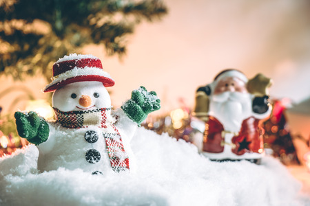 Snowman and Santa claus hold bell among pile of snow at silent night with a light bulb, light up the hopefulness and happiness in Merry christmas and new year night.の写真素材