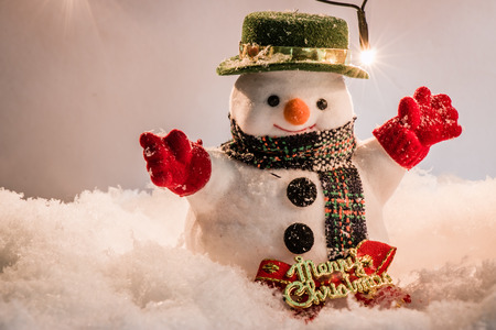 Snowman stand among pile of snow at silent night with a light bulb, light up the hopefulness and happiness in Merry christmas and happy new year night.の写真素材