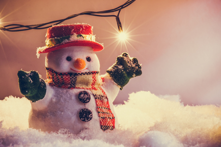 Snowman stand among pile of snow at silent night with a light bulb, light up the hopefulness and happiness in Merry christmas and happy new year night.の写真素材