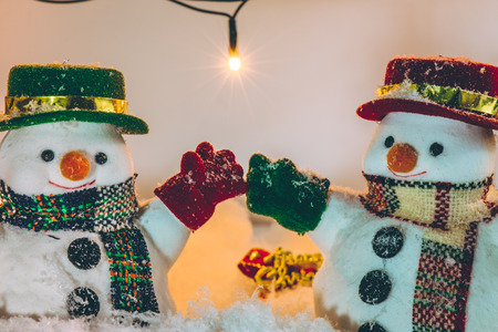 Snowman stand among pile of snow at silent night with a light bulb, light up the hopefulness and happiness in Merry christmas and happy new year night.の写真素材