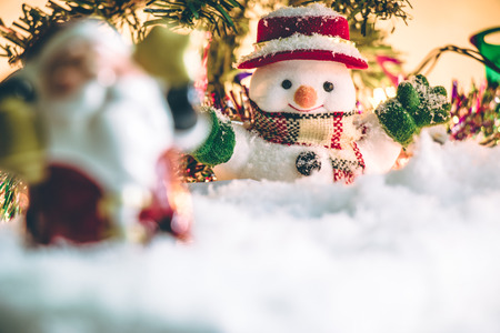 Snowman and Santa claus hold bell among pile snowの写真素材