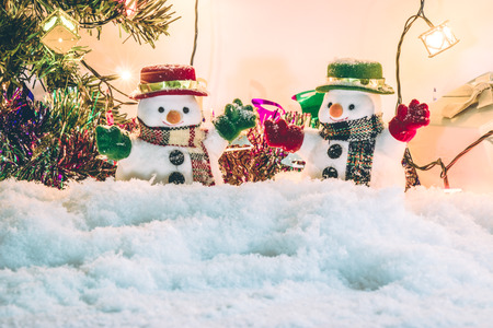 Snowman stand among pile of snow at silent night with a light bulb, light up the hopefulness and happiness in Merry christmas and happy new year night.の写真素材