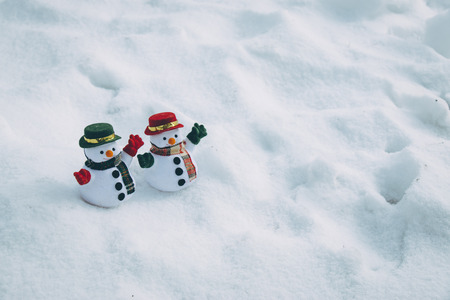 two Snow man stand among pile of snow in park. Sunshine is warming but cold at Hokkaido, Japan.の写真素材
