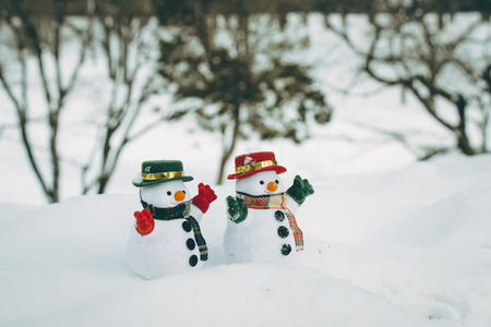 two Snow man stand among pile of snow in park. Sunshine is warming but cold at Hokkaido, Japan.の写真素材