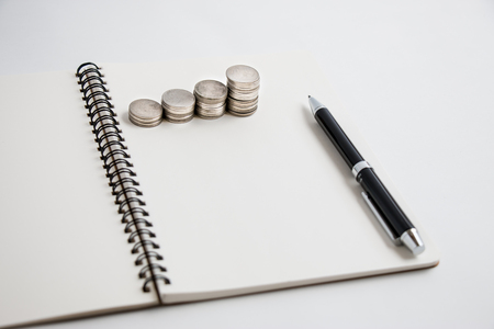 Put pen on notebook and Coin set a graph.の写真素材