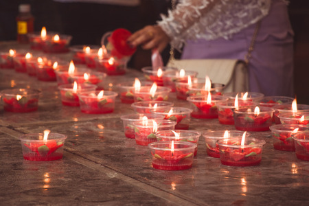 Burning red flower candle at chinese shrine for making merit in chinese new year festival. Pray for New Year,Lighting incense to Buddha.の写真素材