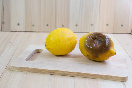 Fresh lemon and rotten lemon put on chopping block, wooden table isolate background.の写真素材