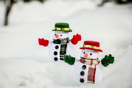 Snowman and friend stand among pile of snow in park. Morning sunshine is warming in winter. Welcome christmas season.の写真素材