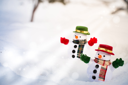 Snowman and friend stand among pile of snow in park. Morning sunshine is warming in winter. Welcome christmas season.の写真素材