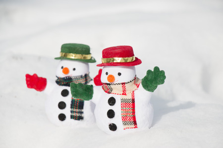 Snowman and friend stand among pile of snow in park. Morning sunshine is warming in winter. Welcome christmas season.の写真素材
