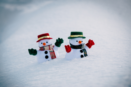 Snowman and friend stand among pile of snow in park. Morning sunshine is warming in winter. Welcome christmas season.の写真素材