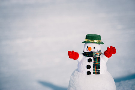 Snow man stand among pile of snow. Morning sunshine is warming in winter.の写真素材