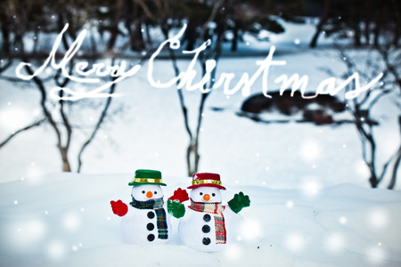 Snowman and friend stand among pile of snow in park. Morning sunshine is warming in winter. Welcome christmas season.の写真素材