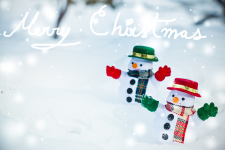 Snowman and friend stand among pile of snow in park. Morning sunshine is warming in winter. Welcome christmas season.の写真素材