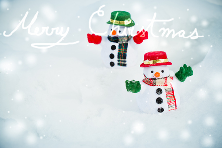 Snowman and friend stand among pile of snow in park. Morning sunshine is warming in winter. Welcome christmas season.の写真素材