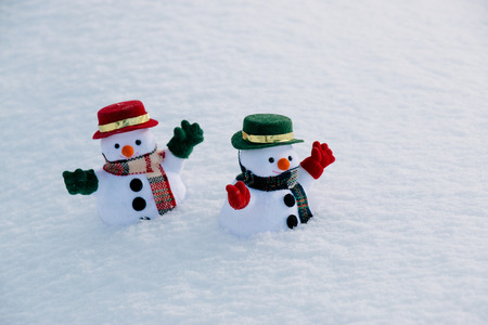 Snowman and friend stand among pile of snow in park. Morning sunshine is warming in winter. Welcome christmas season.の写真素材